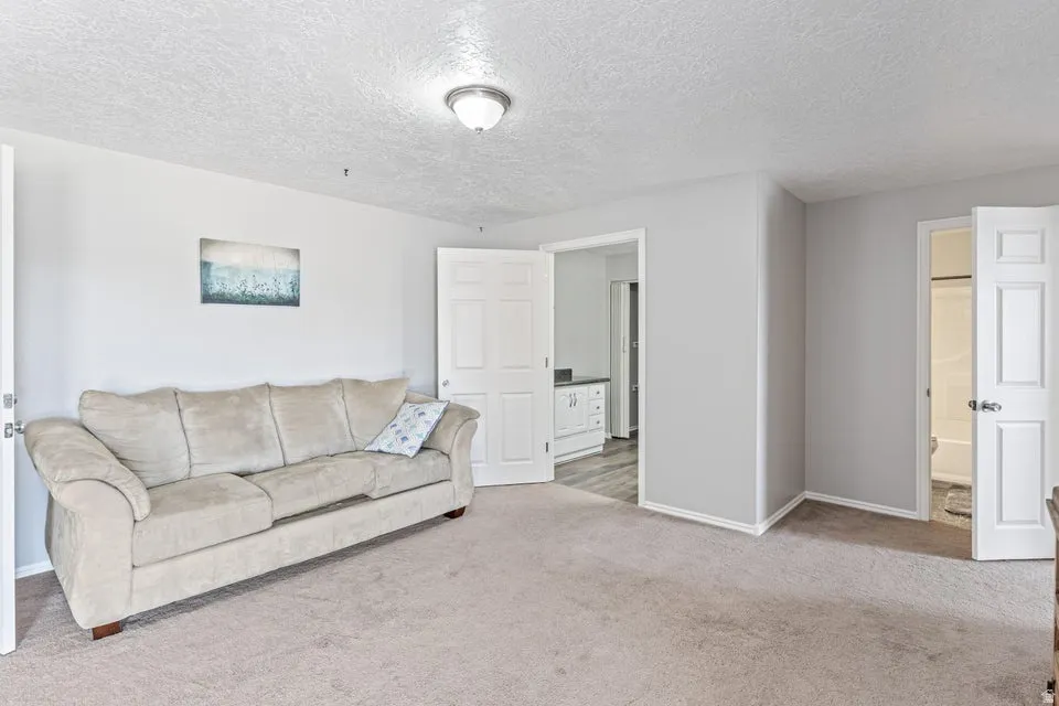 Carpeted room with a textured ceiling and neutral wall tones
