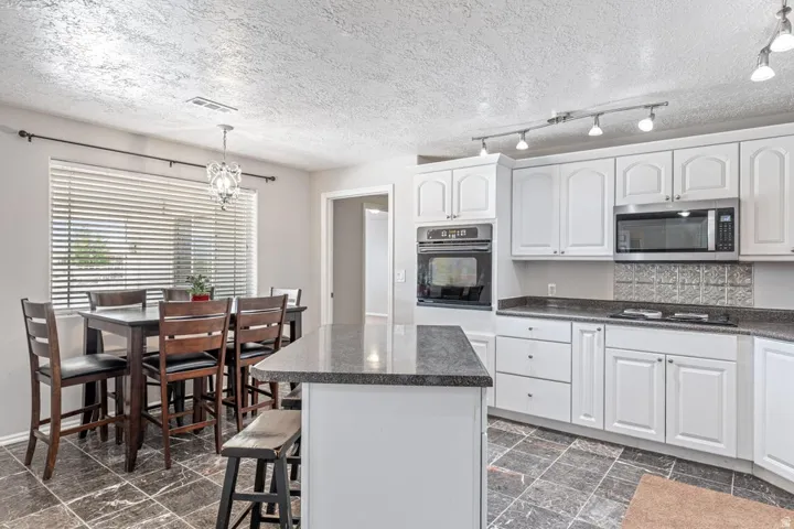 Kitchen featuring white cabinetry, dark stone countertops, stainless steel microwave, and built-in oven