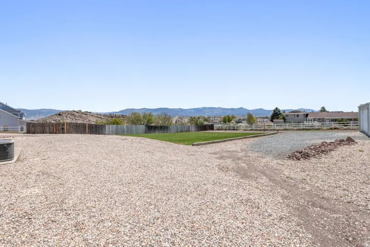 Expansive gravel area with a green lawn portion and partial wood fencing