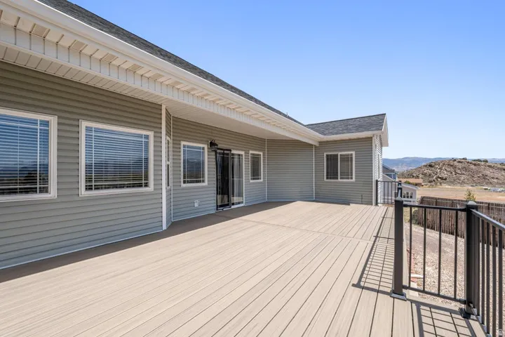 Expansive outdoor deck featuring composite decking, black metal railings, and a sliding glass door