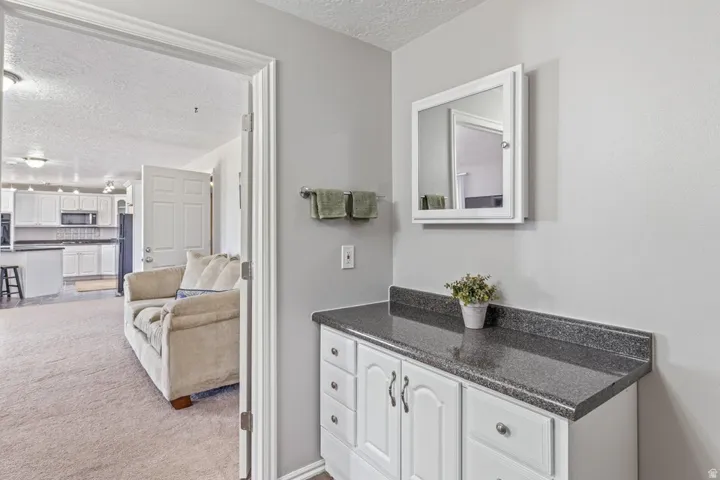 Vanity area featuring a white cabinet with dark hardware, a dark speckled countertop, and a wall-mounted medicine cabinet with a mirror