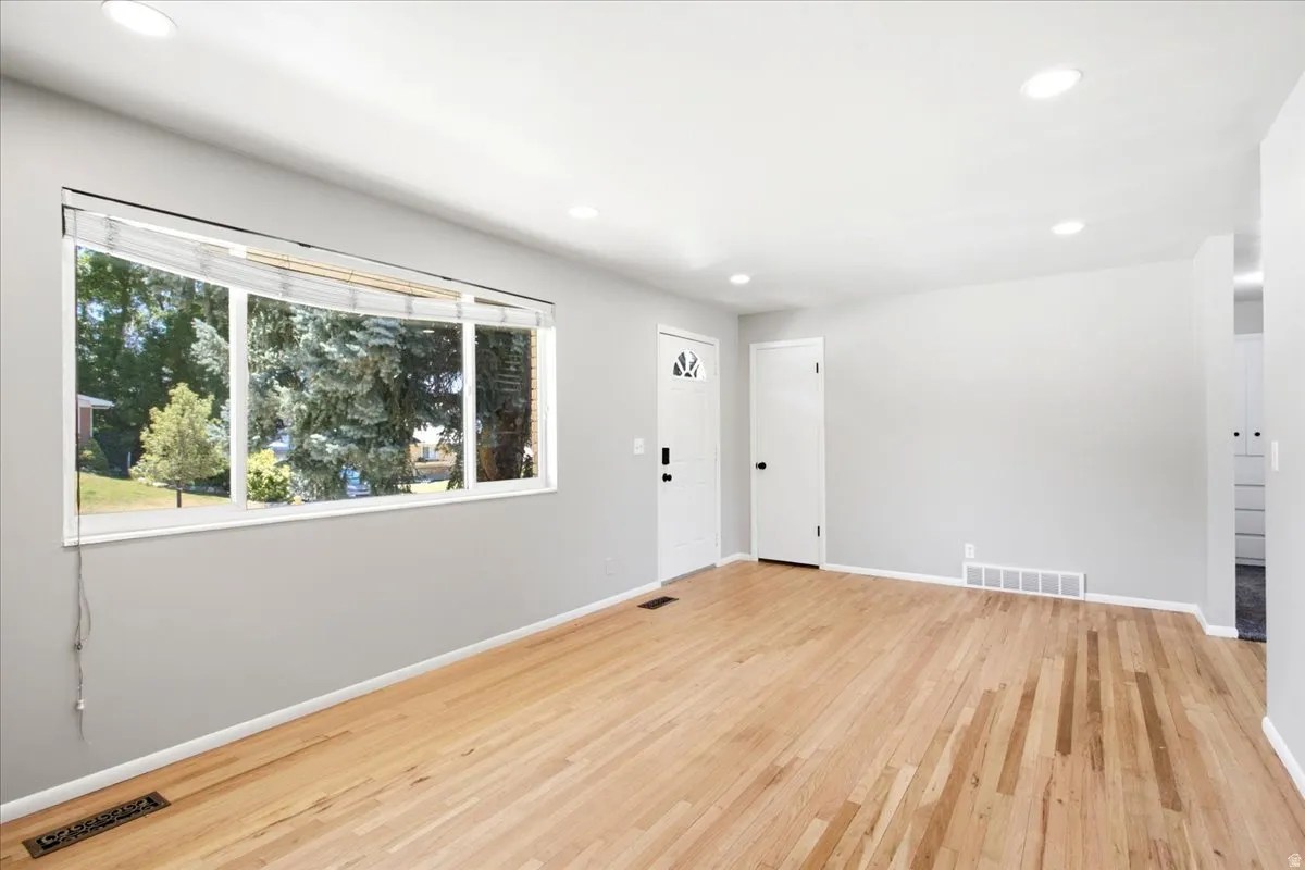 Spacious room featuring wood-finish flooring, light grey walls, and a large bay window