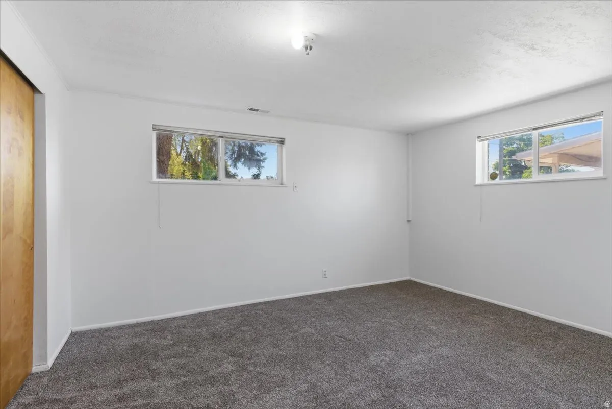 Spacious room featuring gray carpet flooring, white painted walls, and two horizontal windows