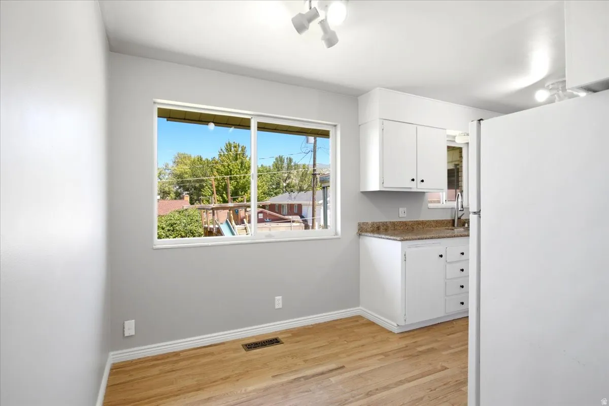Kitchen area featuring white cabinetry, granite-finish countertops, and stainless steel sink