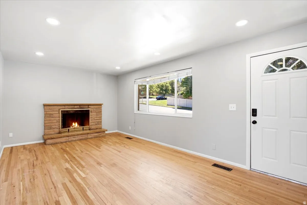 Living space featuring wood-finish flooring, a stone-clad fireplace, and recessed lighting