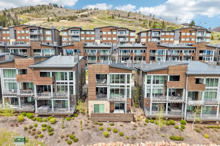 Contemporary multi-level exterior residences featuring wood paneling, extensive glass facades, multiple private balconies, ground-level patios, and integrated hot tubs