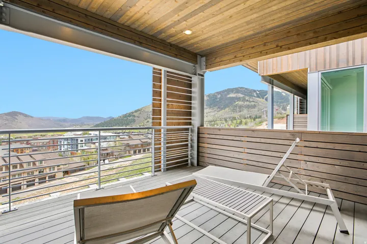 Expansive balcony featuring a composite deck, wood paneling, wood-finish ceiling, and metal railing