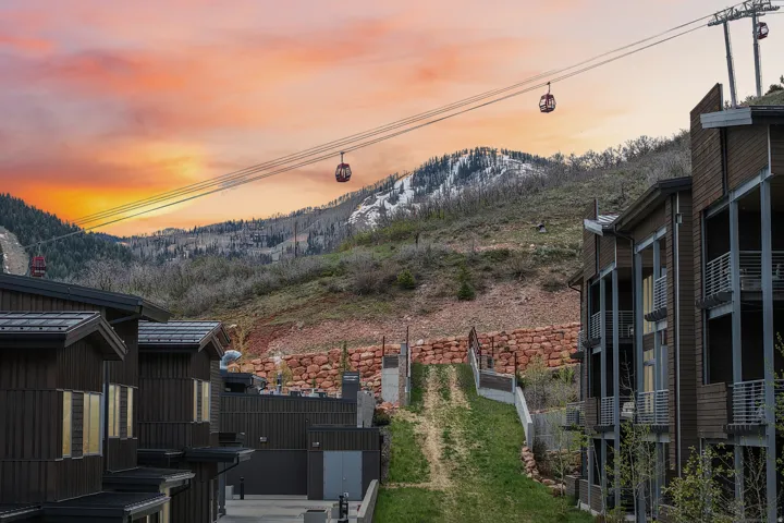 Mountain landscape with gondola system, featuring multi-level buildings with dark siding and balconies