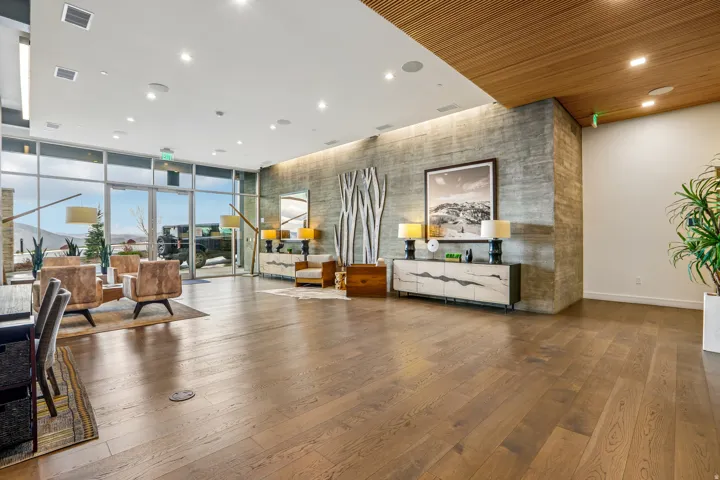 Spacious interior featuring wide plank wood-finish flooring, a full wall of floor-to-ceiling windows, and a concrete-finish accent wall