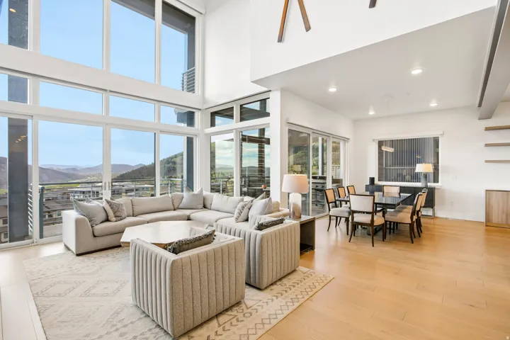 Expansive living space featuring floor-to-ceiling windows, wood-finish flooring, and a dining area with recessed lighting
