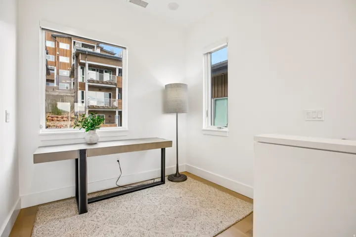 Recessed lighting illuminates this bright space featuring two windows, light wood-finish flooring, and crisp white walls