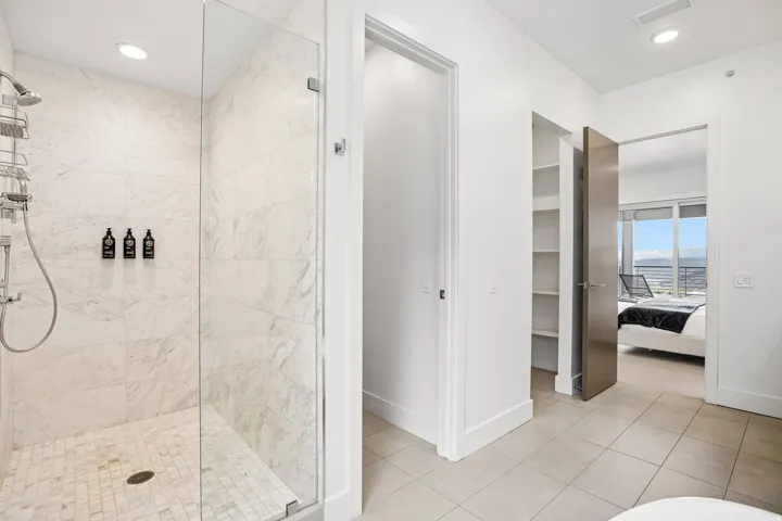 Spacious shower with large format tile walls and a mosaic tile floor, featuring a glass enclosure