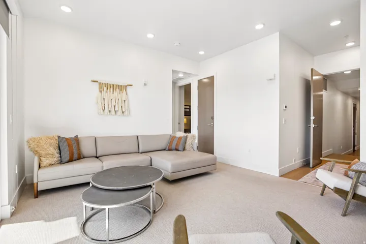 Spacious living area featuring neutral carpeting and recessed lighting
