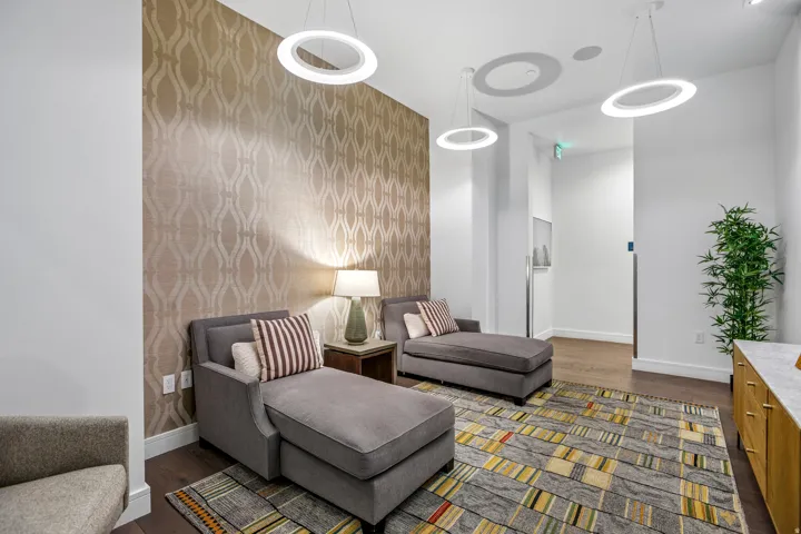 Accent wall with textured wallpaper, dark wood-finish flooring, recessed lighting, and modern ring pendant lights