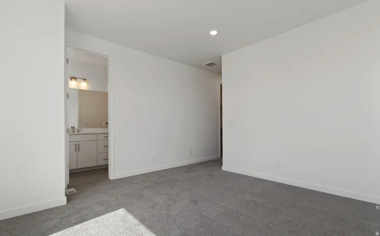 Spacious room with gray carpeting and crisp white walls