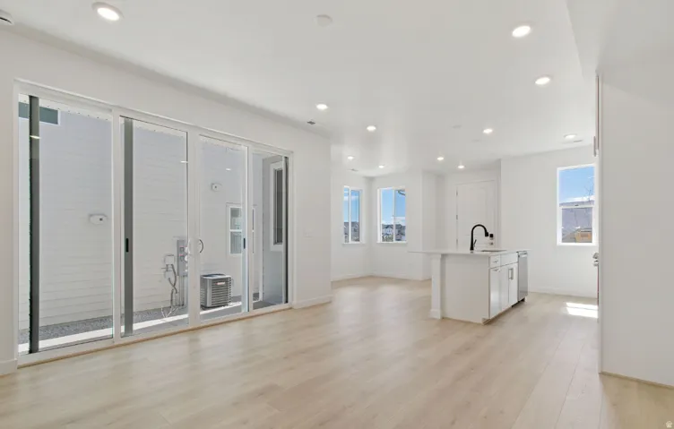 Open-concept living area featuring light wood-finish flooring, recessed lighting, and white walls