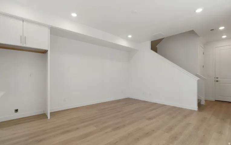Spacious open room featuring wood-finish flooring, recessed lighting, and white baseboards
