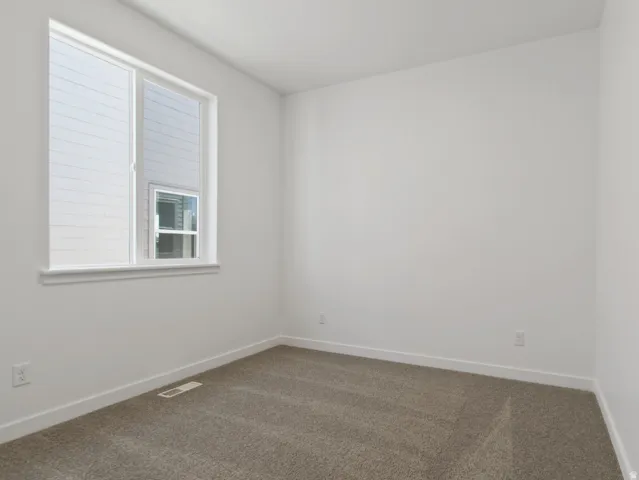 Room featuring a large window with white trim, neutral carpeting, white walls, and white baseboards