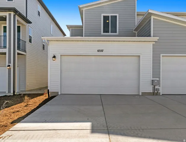 Contemporary facade featuring light grey and white siding, a prominent two-car garage, and a concrete driveway
