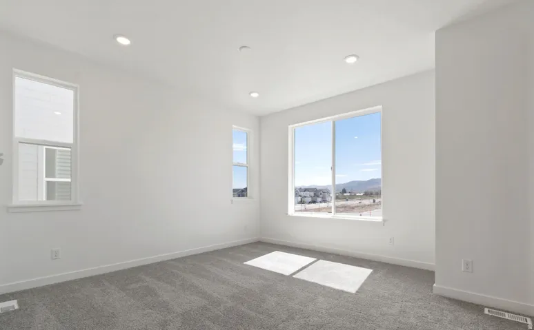 Bright interior space featuring a large picture window, two additional windows, recessed ceiling lighting, and neutral carpeting