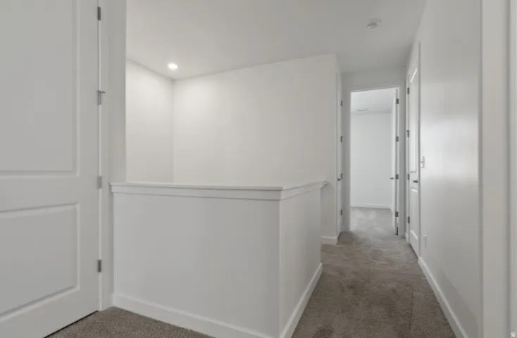 Upper-level landing featuring neutral carpeting, white interior doors, and recessed lighting