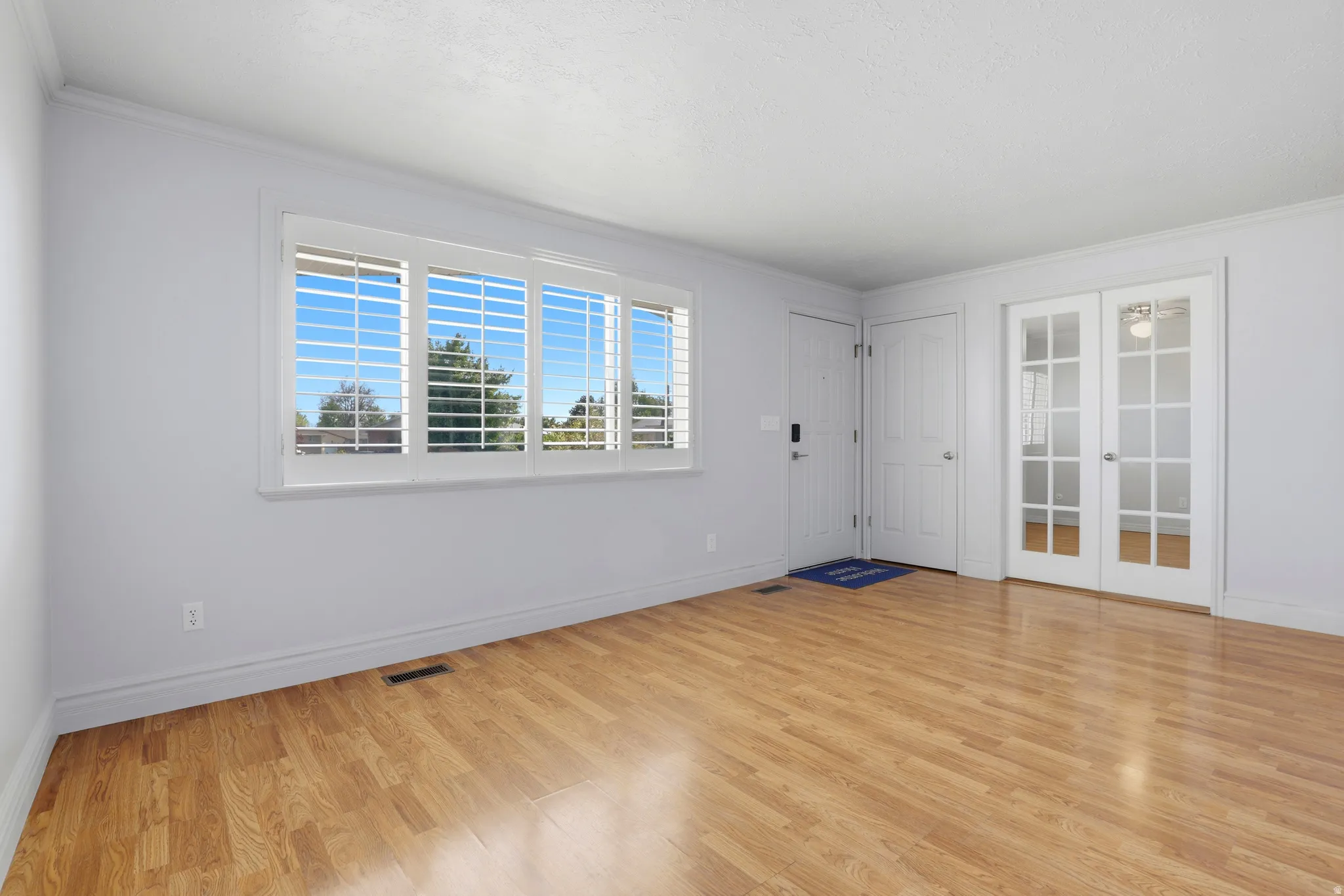 Expansive room featuring light wood-finish flooring, white walls, and crown molding