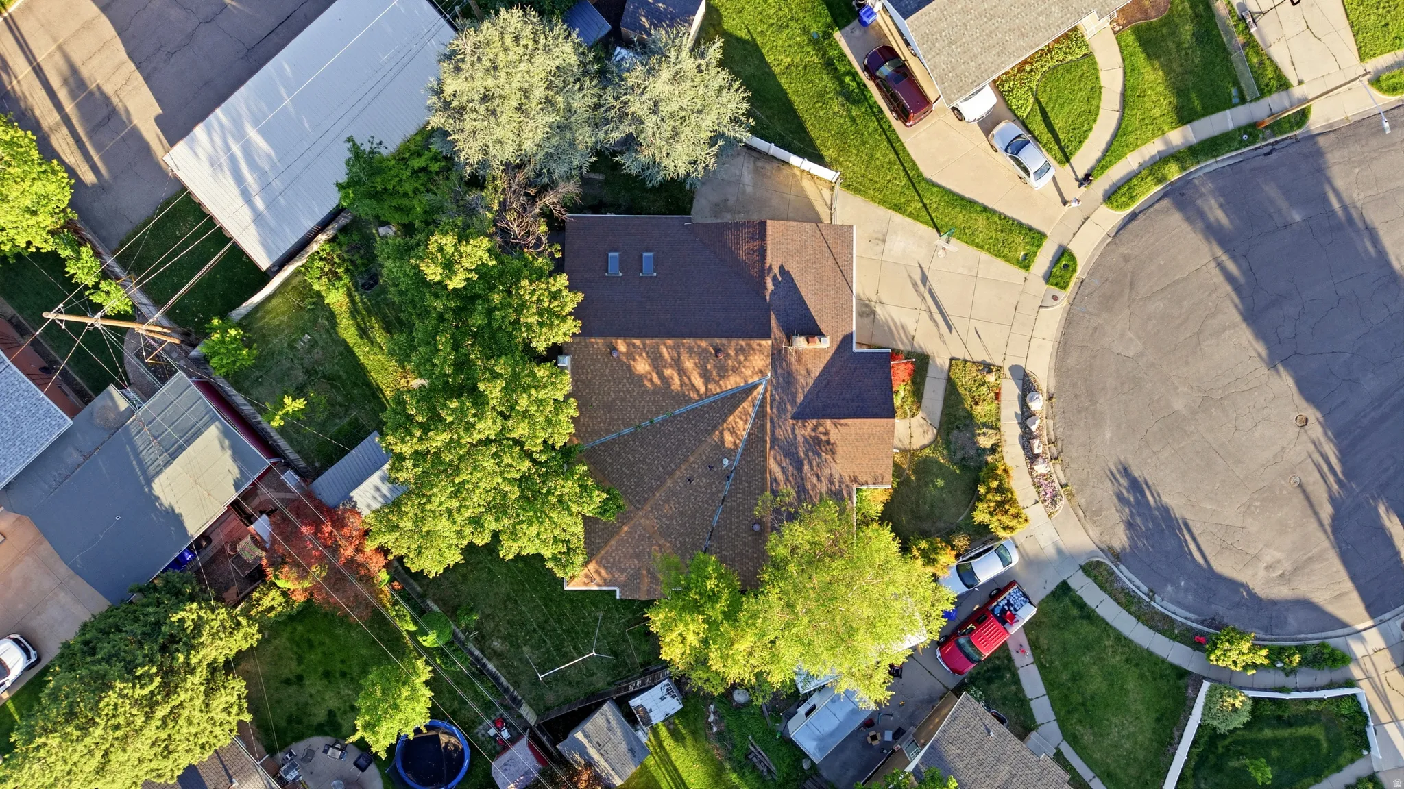 Traditional home with a shingled roof, mature trees, and a paved driveway