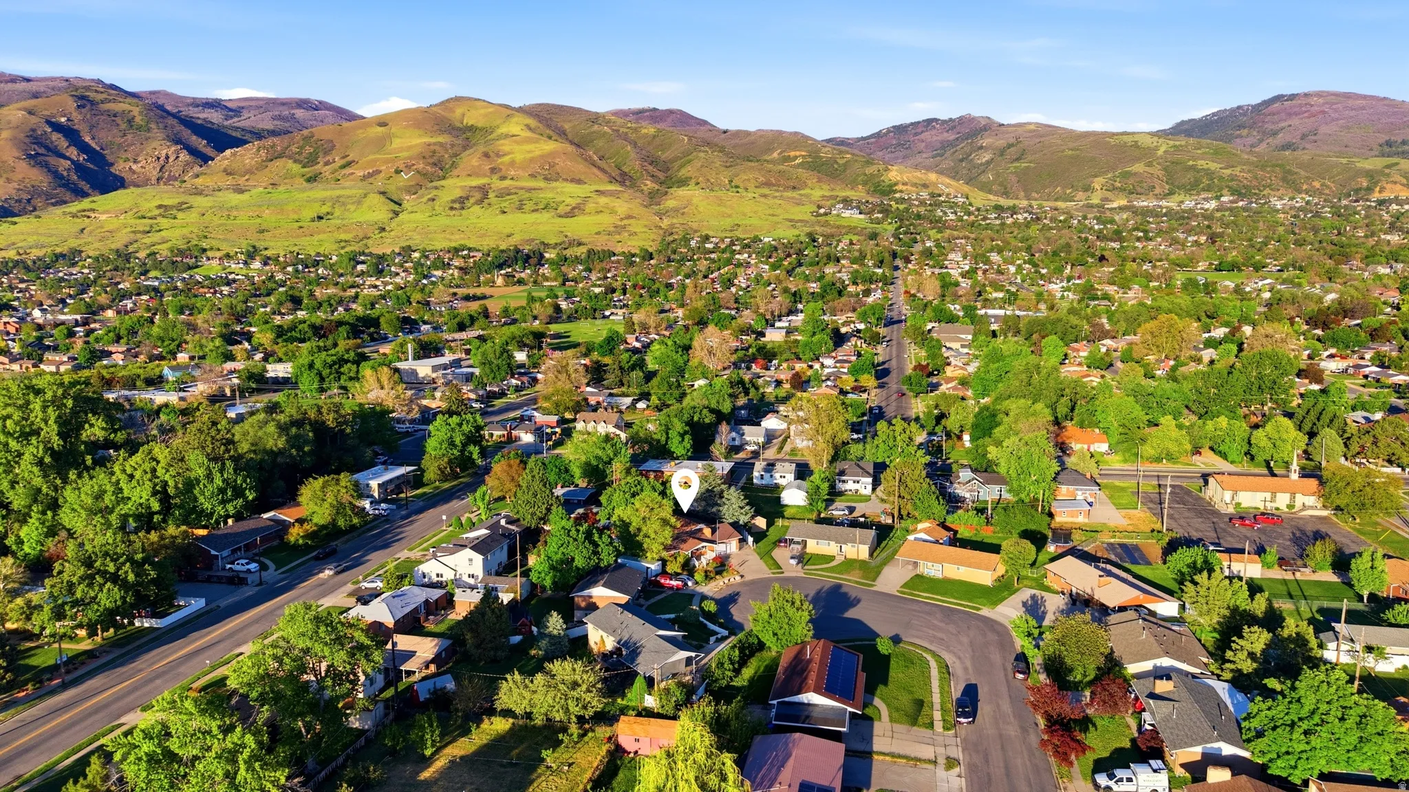 Residential neighborhood featuring mature trees and a backdrop of green mountains