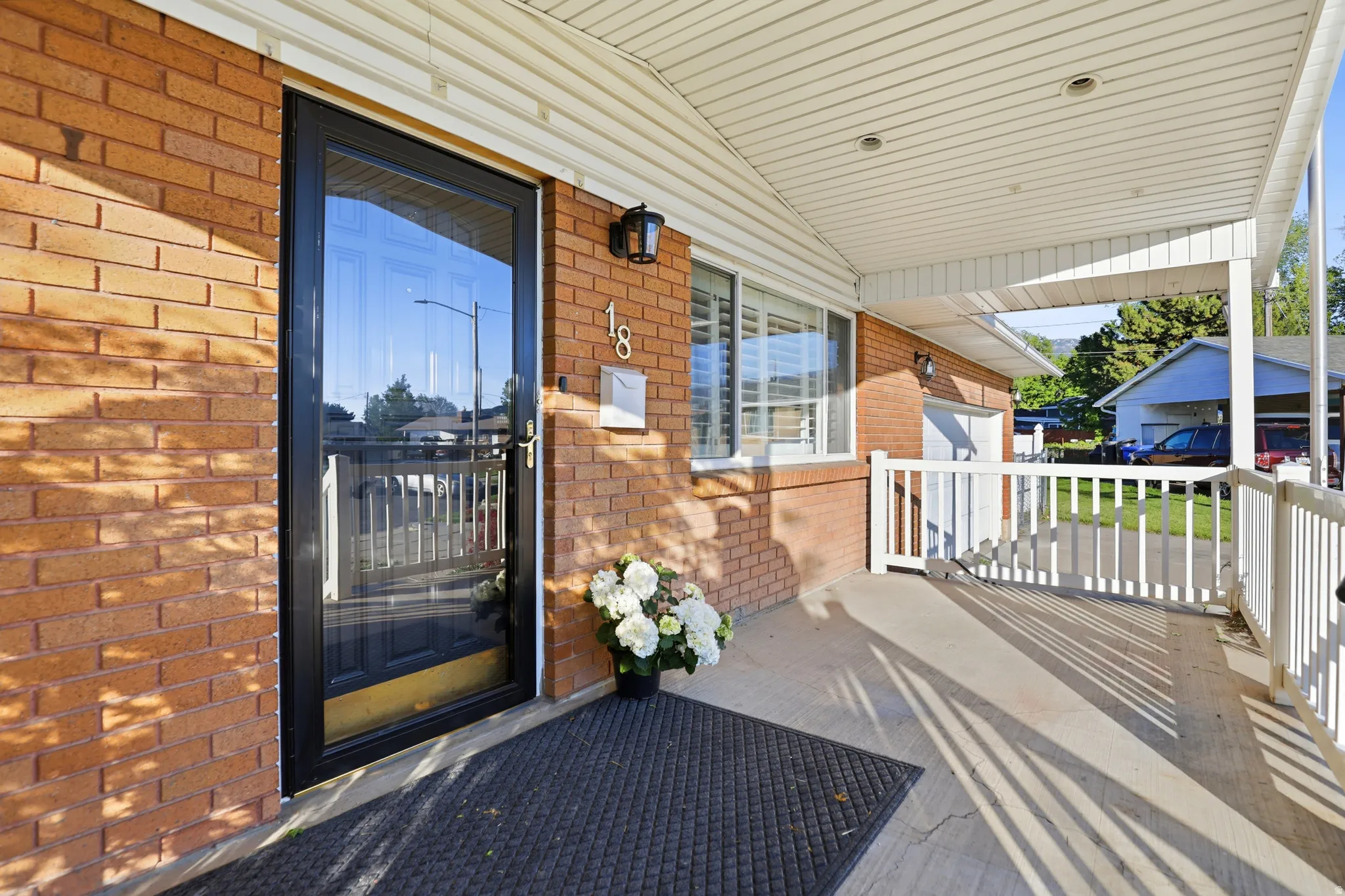 Brick exterior featuring a covered porch with white railing, recessed lighting, and a glass-paneled storm door