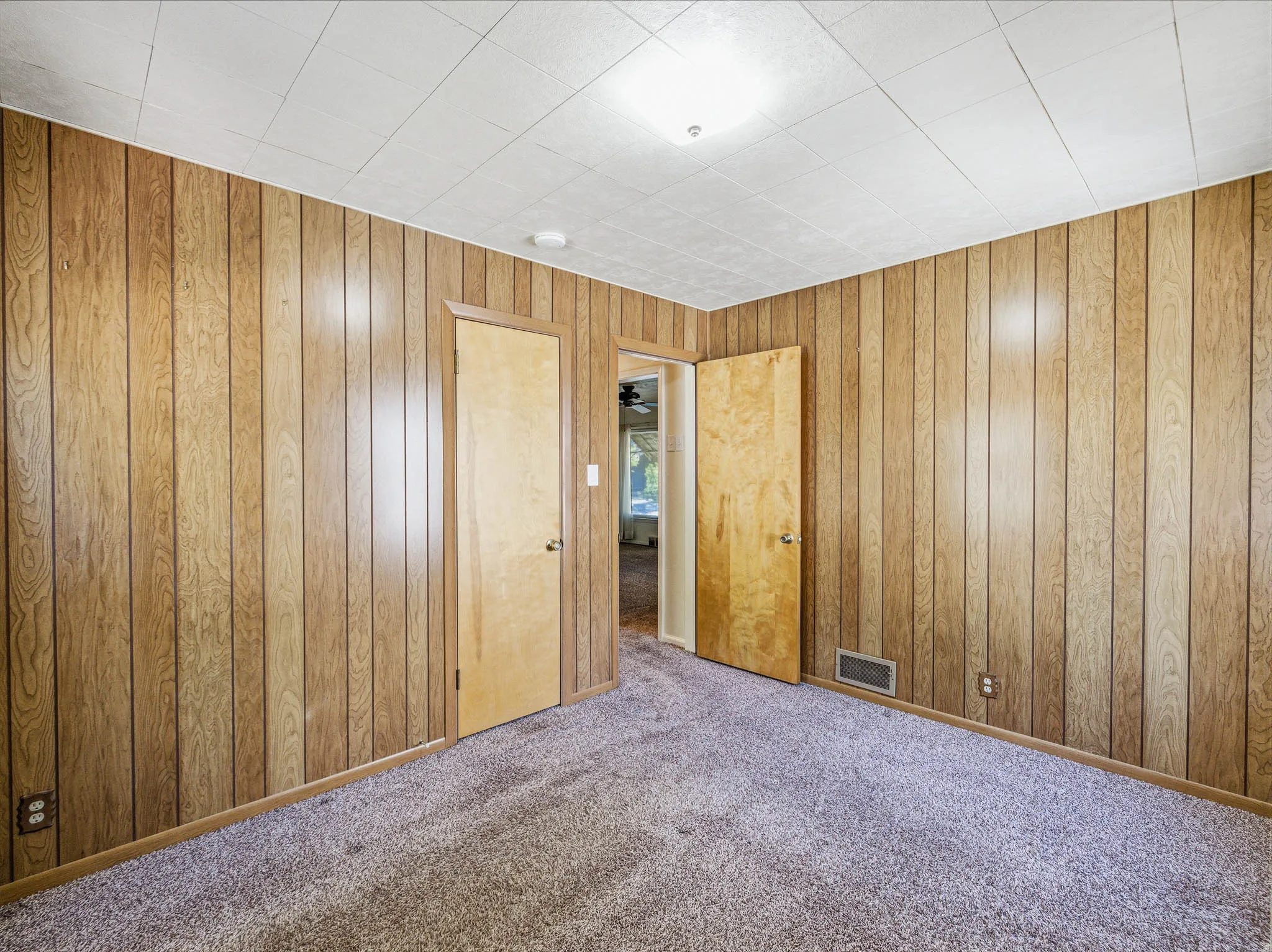 Room featuring wood-paneled walls, a textured ceiling, and gray carpet flooring