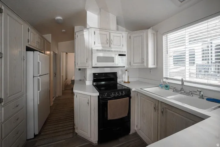 Kitchen featuring light wood-finish cabinetry, white countertops, and a full suite of white and black appliances