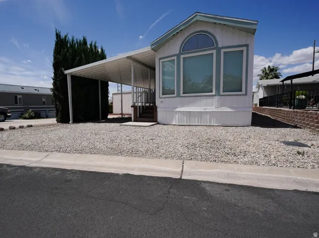White exterior with light blue trim and a covered carport