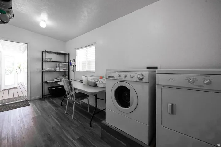 Utility room featuring wood-finish flooring, a window with blinds, and a rear exterior door with a deck beyond