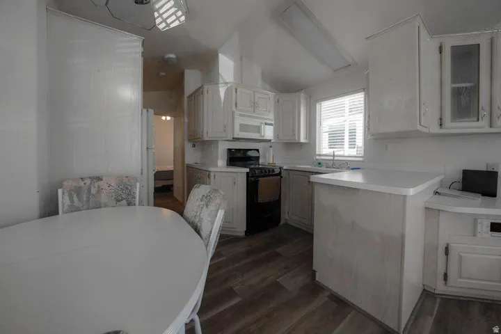 Kitchen featuring white cabinetry, wood-finish flooring, a built-in microwave, and a black range