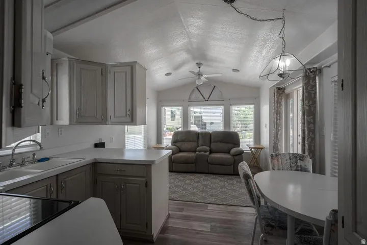 Integrated kitchen and living area featuring a vaulted ceiling and wood-finish flooring