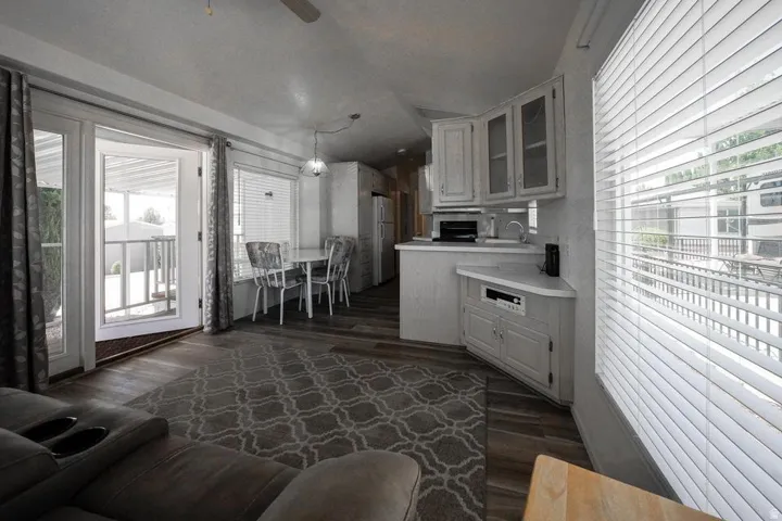 Open-concept living space featuring wood-finish flooring, white cabinetry, and French doors leading to an outdoor porch with railings
