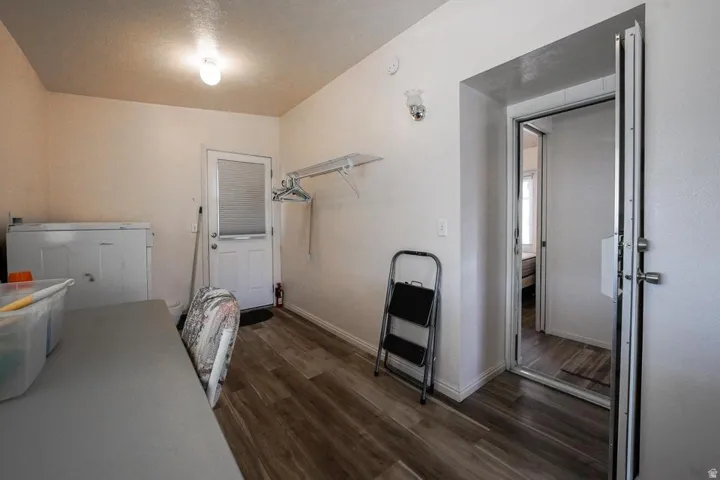 Utility room featuring wood-finish flooring, a white back door with frosted glass, and a wall-mounted shelf