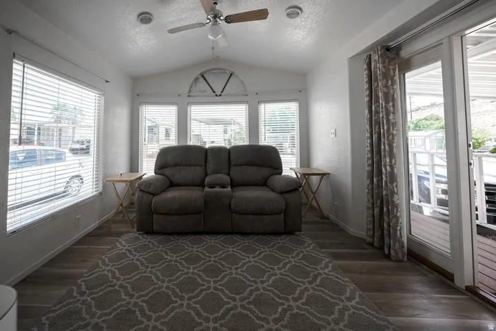 Spacious room featuring vaulted ceilings, wood-finish flooring, and multiple windows with blinds