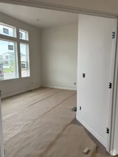 Bright office  with white painted walls, multi-pane windows, baseboard trim, and a doorway.