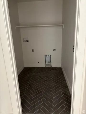 Laundry area, in basement with herringbone pattern floor tiling, white walls, and a built-in storage shelf