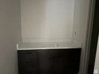Dark wood-finish vanity with a white countertop and integrated sink.Vanity area in basement bathroom