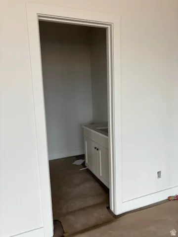 Compact bathroom space featuring a white vanity cabinet with double doors and black hardware