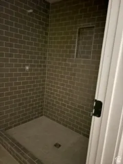 Big Shower enclosure featuring dark subway tile walls, a built-in shower niche, and a concrete-finish shower pan.This is a great basement bathroom.