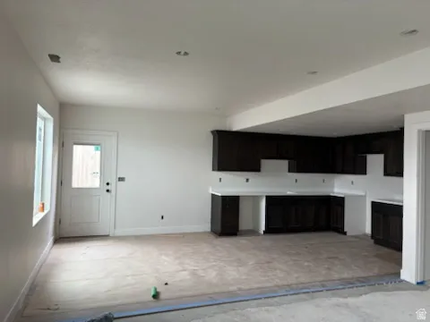 Open-concept room featuring dark wood-finish cabinetry, white countertops, and a white paneled door with a glass insert.Separate access to outside.