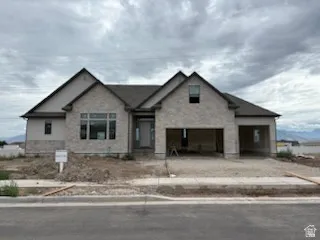 New construction residence with a multi-gabled roofline and light-toned brick and siding exterior
