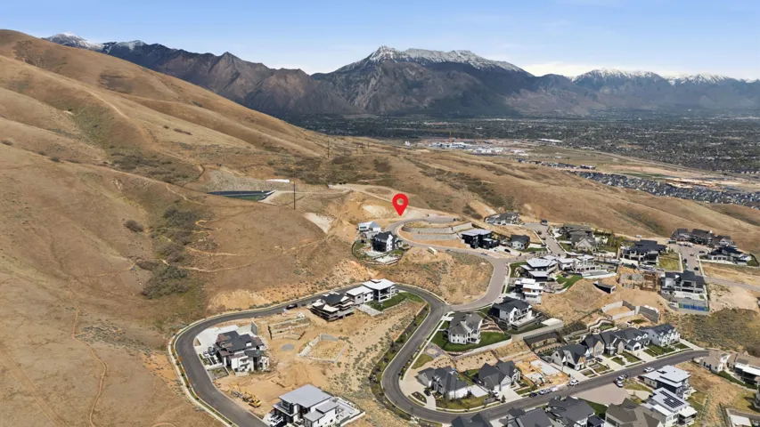 Hillside property featuring mountain backdrop, established surrounding homes, paved roads, and extensive undeveloped land