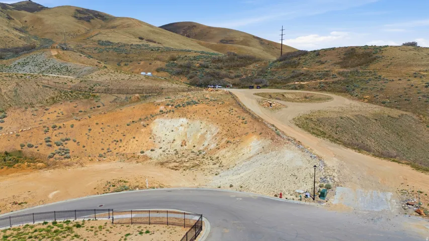 Paved road with cul-de-sac turn, bordering a natural landscape of rolling hills
