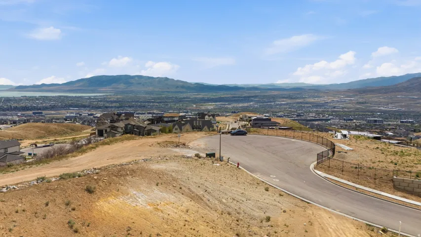 Elevated residential area with a paved road, distant urban landscape, and mountainous horizon