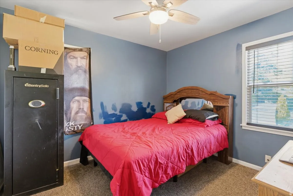 Bedroom featuring a ceiling fan with integrated lighting, a window with blinds, and carpeted flooring
