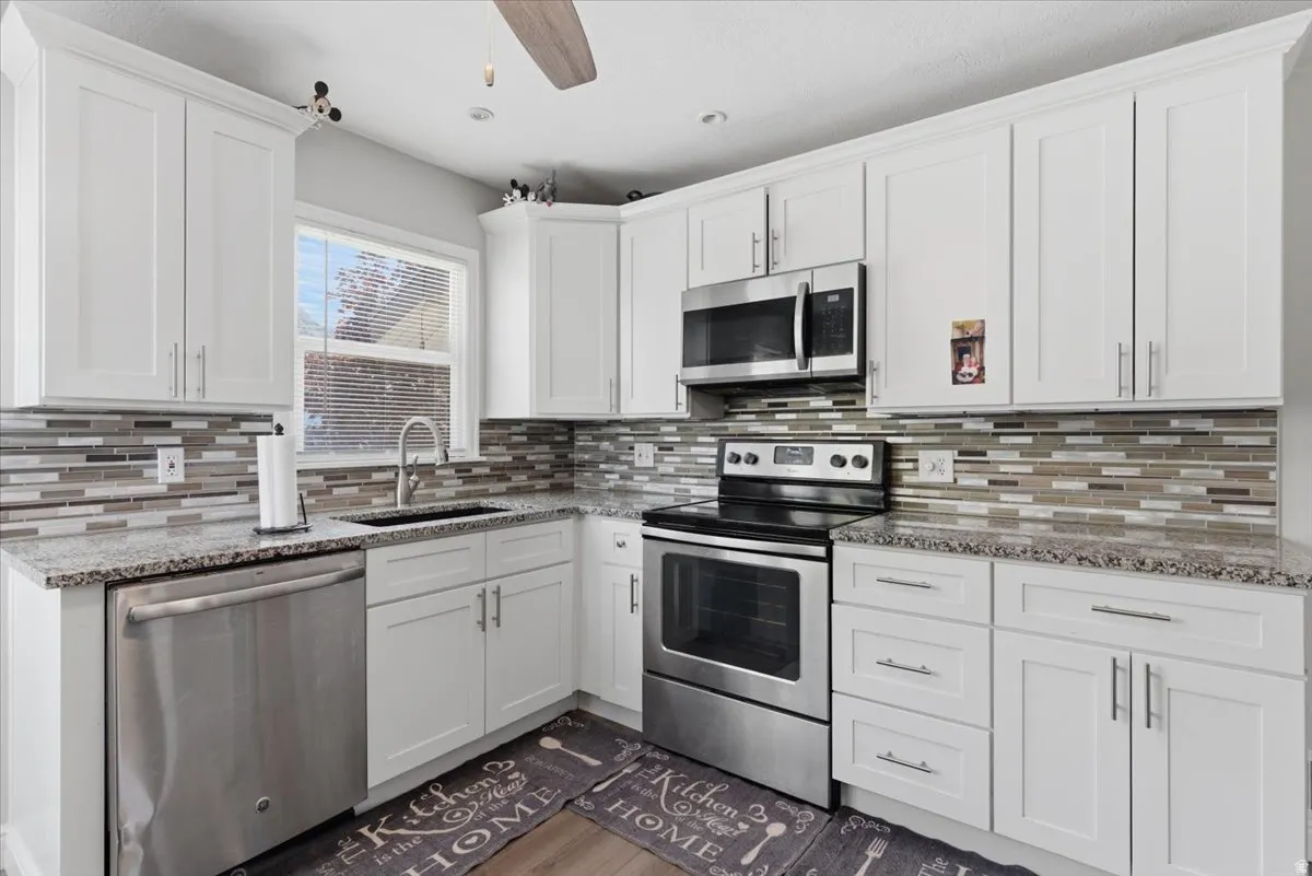 Kitchen featuring white shaker-style cabinetry, granite countertops, and a mosaic tile backsplash